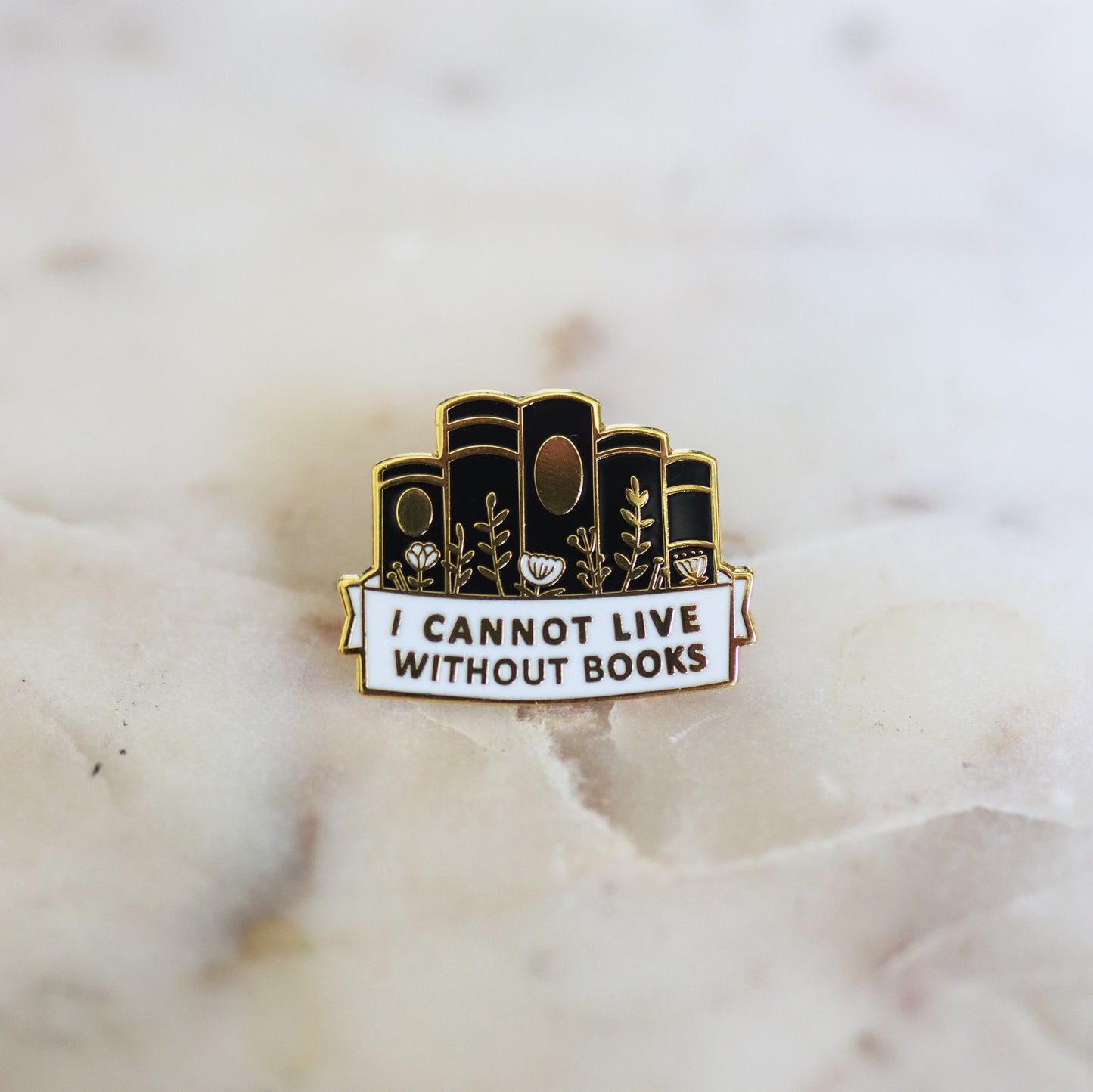 A pin shaped like a stack of black books with the phrase I Cannot Live Without Books. From Copper Crow Swag Market's Book Pins collection