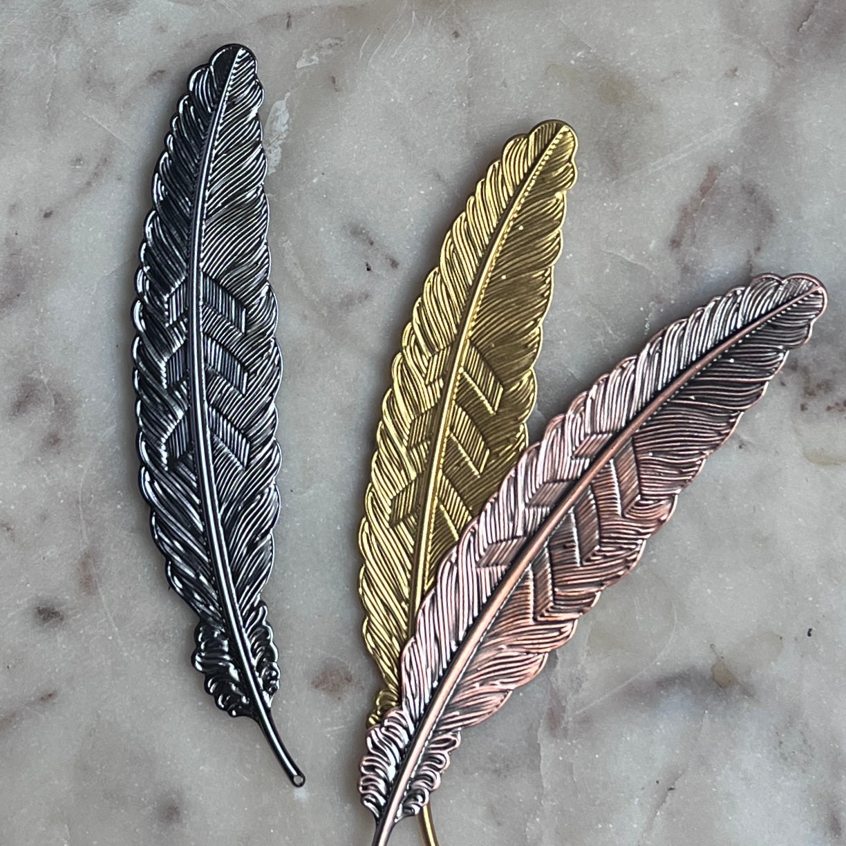 Gold metal feather-shaped bookmark from Copper Crow Swag Market