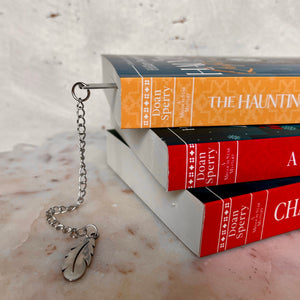 The spines of three Missouri Star Mystery books and a feathered bookmark